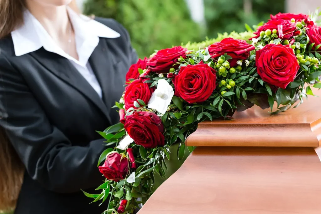 Composition de fleurs de deuil en roses rouges sur un cercueil.