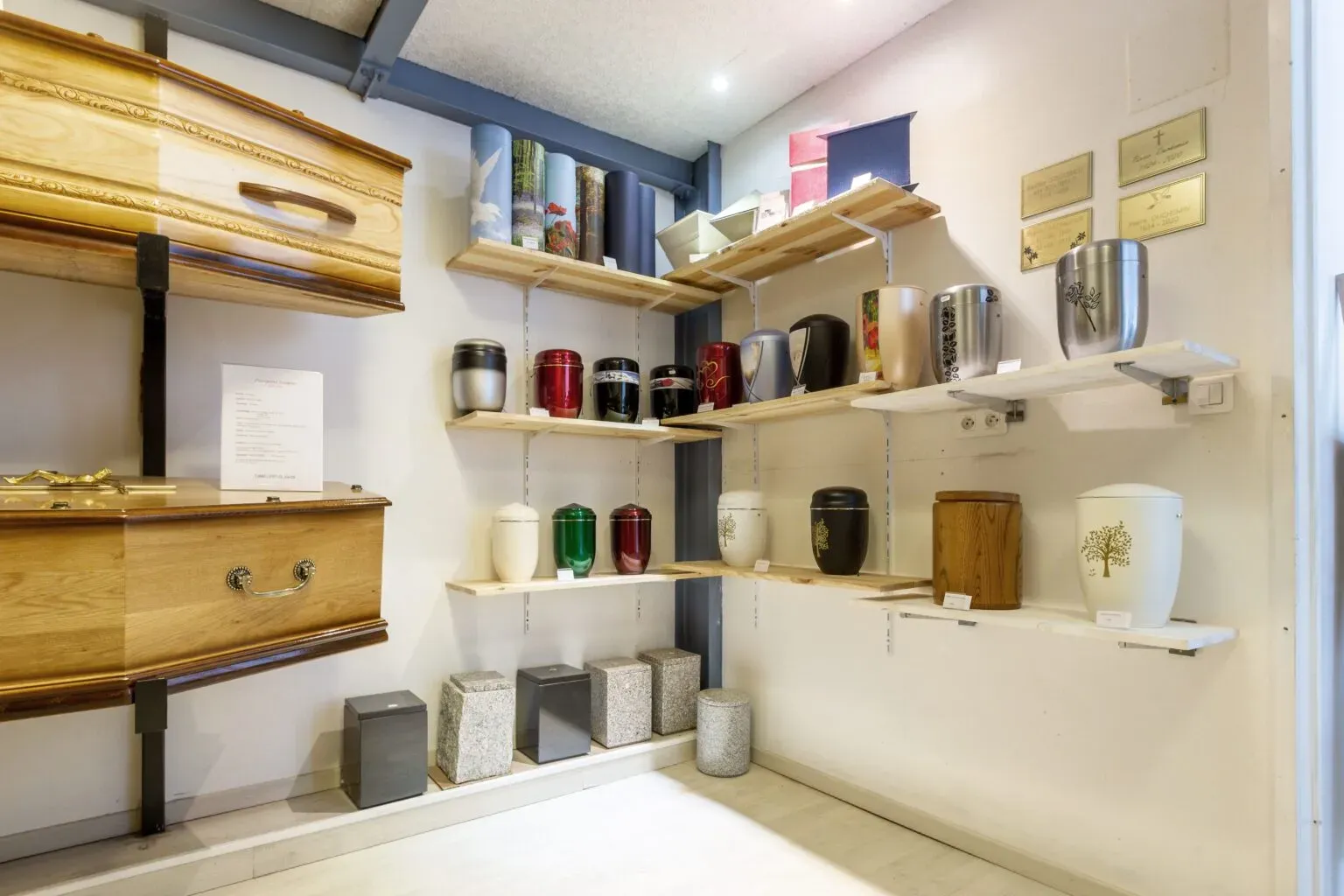 Exposition de cercueils en bois et urnes funéraires dans une boutique de deuil.